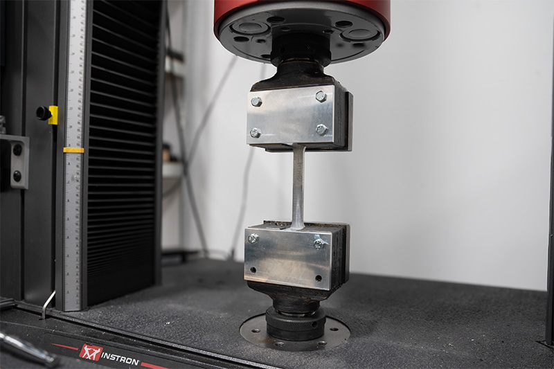 a component is undergoing a pull test in the instron universal mechanical tester