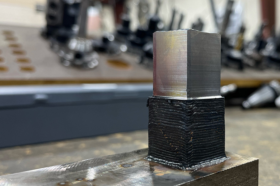 A rectangular alloy block that has been wire-laser metal 3D printed and then the top half milled to a smooth finish within a hybrid manufacturing system.